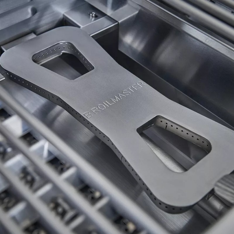 Broilmaster grilling accessory placed inside a stainless steel grill, showcasing its durable design and ventilation holes for optimal cooking performance.