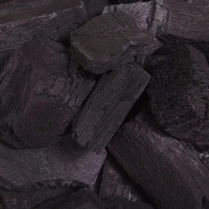 Close-up of natural charcoal pieces, showcasing their dark, textured surfaces, ideal for grilling and barbecuing.