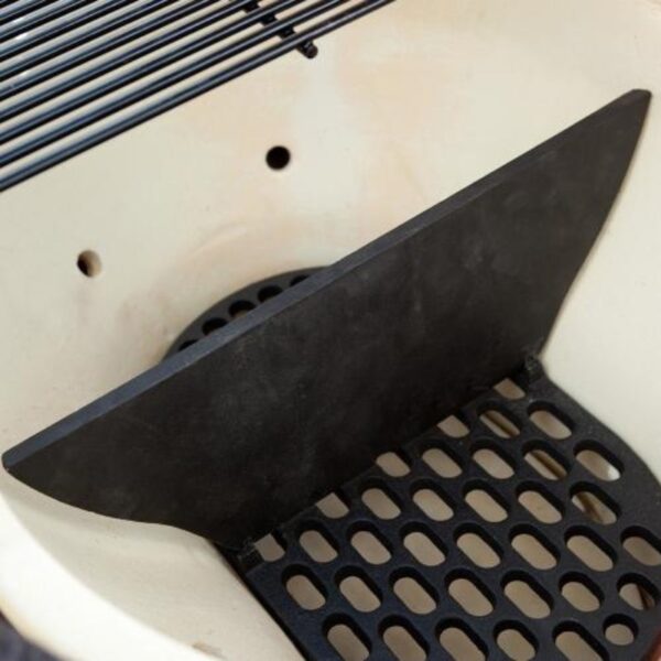 Close-up of a black ceramic heat deflector inside a barbecue grill, designed for indirect cooking and heat distribution.