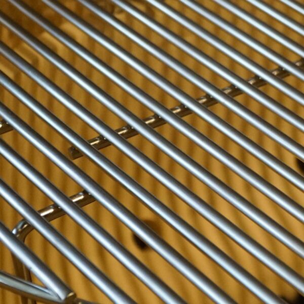 Close-up of a stainless steel grilling grate with parallel bars, showcasing its durable construction for optimal heat distribution and grilling performance.