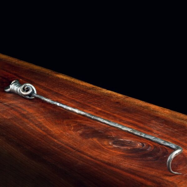 Decorative metal hook with a spiral design, resting on a polished wooden surface.