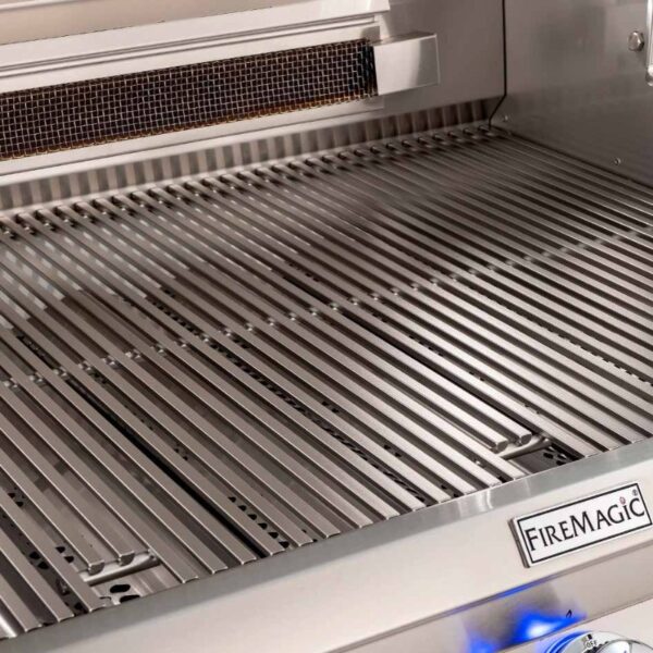 Stainless steel grill surface of a Fire Magic barbecue, featuring evenly spaced cooking grates and an integrated control panel.