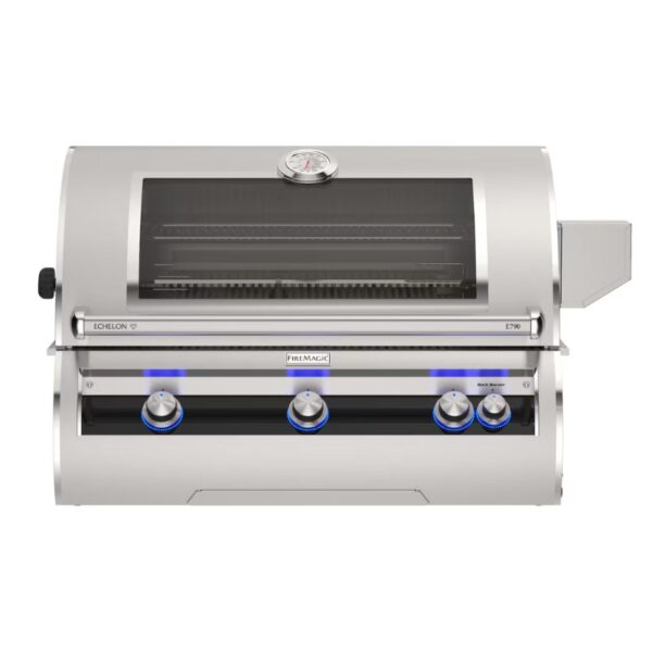 Stainless steel Fire Magic Echelon E790 gas grill featuring a viewing window, temperature gauge, and illuminated control knobs for outdoor cooking.