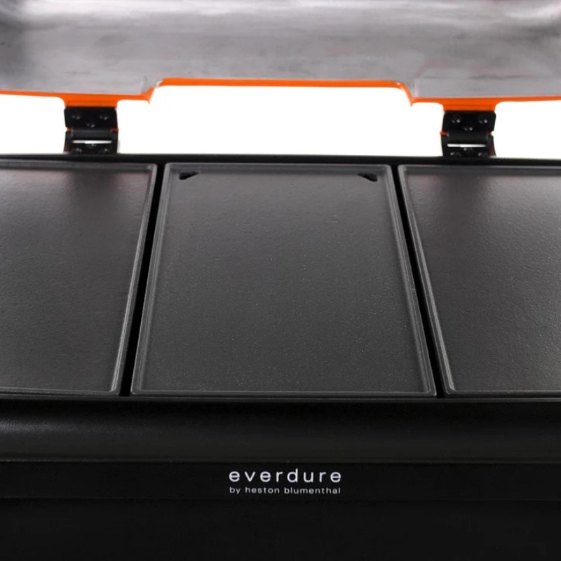 Close-up of the Everdure barbecue grill top, featuring three detachable cooking plates and a sleek black finish. The lid is highlighted with an orange trim, showcasing the modern design.