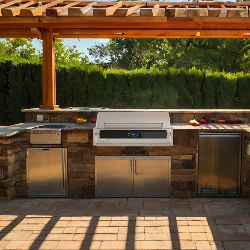 Outdoor kitchen featuring a built-in grill, stainless steel appliances, and stone countertops under a pergola. Lush greenery is visible in the background, enhancing the outdoor cooking experience.