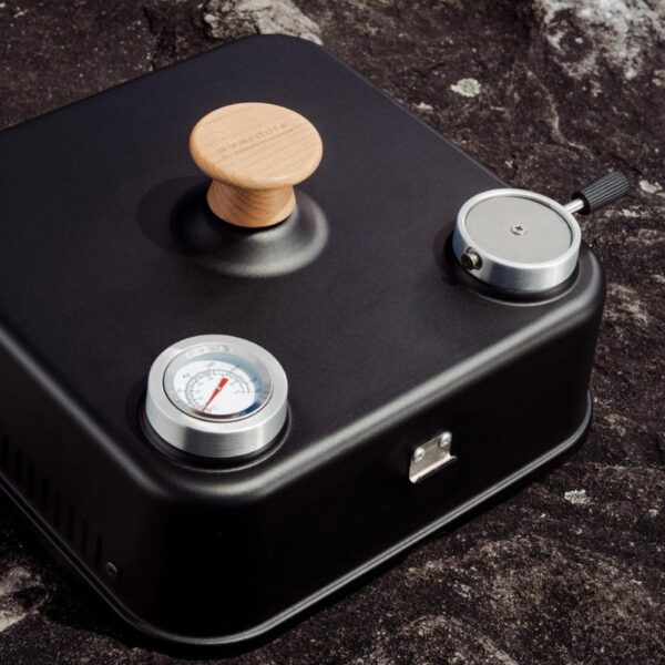 A compact black cooking appliance featuring a wooden handle, pressure gauge, and ventilation controls. Ideal for outdoor grilling or cooking.