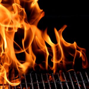 Flames dancing over a grill with a dark background, showcasing the vibrant colors and movement of fire.