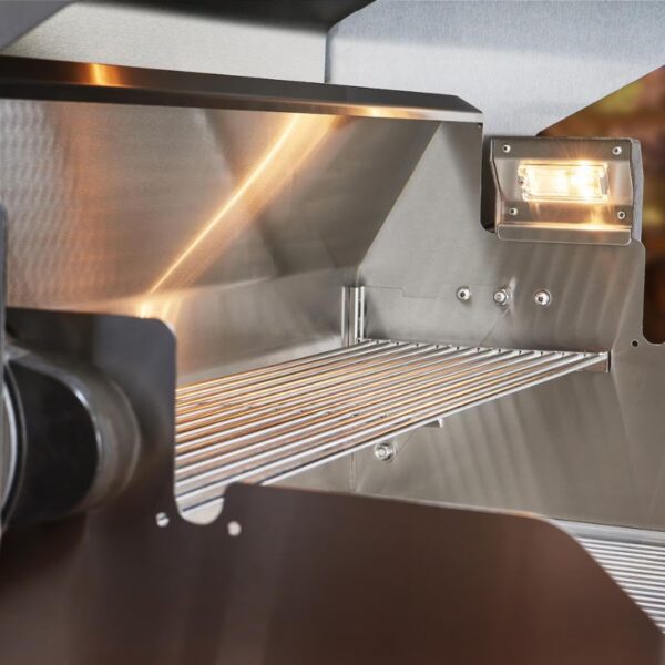 Interior view of a stainless steel grill, showcasing a spacious cooking area with a wire rack and integrated lighting for enhanced visibility while grilling.