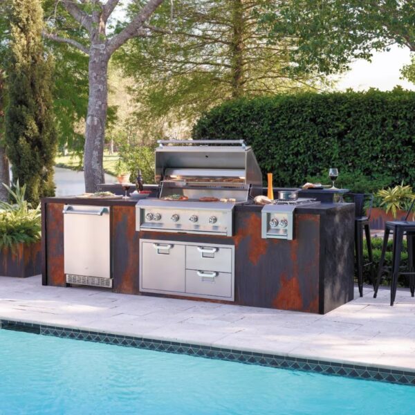 Outdoor kitchen featuring a modern stainless steel grill, storage drawers, and fridge, surrounded by lush greenery and a pool, ideal for entertaining and outdoor cooking.