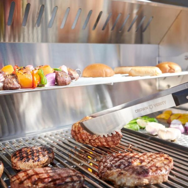 Grilling a variety of meats and vegetables on a stainless steel barbecue, featuring skewers of colorful veggies and burger buns above.