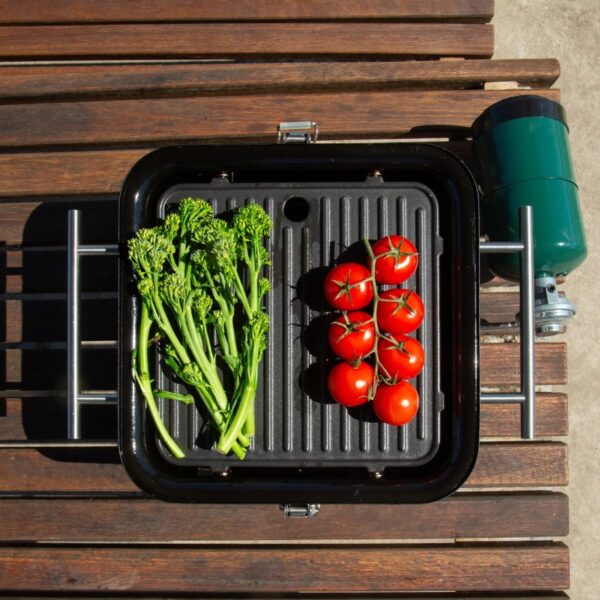 Grill with fresh cherry tomatoes and broccolini on a wooden table, featuring a propane tank on the side.