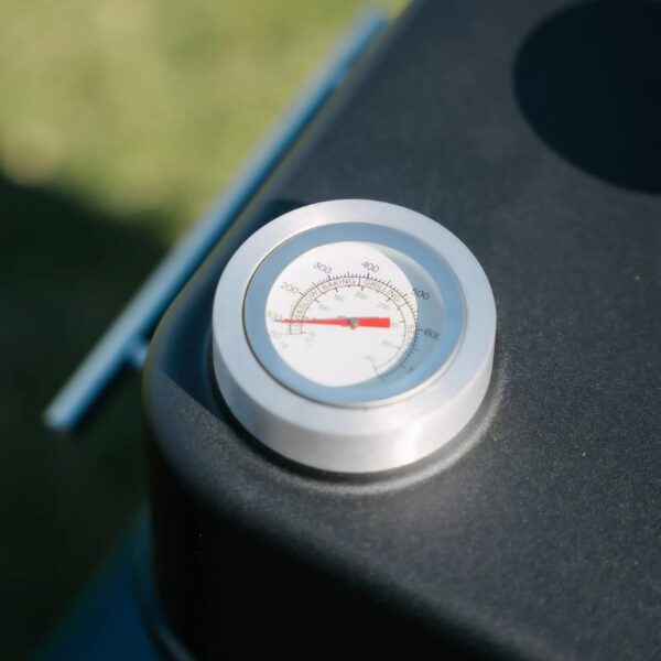 Thermometer gauge on a grill, displaying temperature range for optimal cooking conditions.