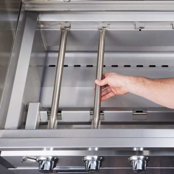 Hand adjusting burners inside a stainless steel gas grill with control knobs visible.