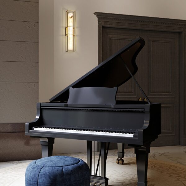 A black grand piano with its lid raised, positioned in a stylish room featuring a plush blue ottoman and elegant wall lighting.
