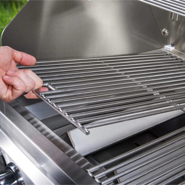 Hand removing a stainless steel grill rack from a barbecue, showcasing the interior of the grill.