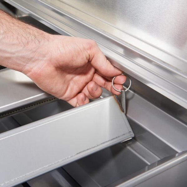 Hand inserting a metal key into a drawer lock of a silver storage unit, demonstrating secure access.