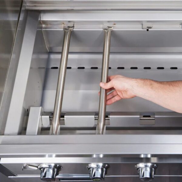 Hand adjusting stainless steel burners inside a modern gas grill.