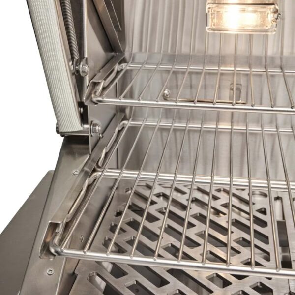 Stainless steel grill interior showcasing two wire racks and a bottom drainage tray, illuminated by an overhead light.