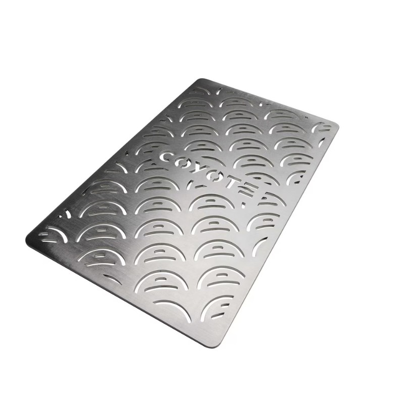 Stainless steel grill mat with a wave pattern and the word "COYOTE" cut out, designed for outdoor cooking and grilling.