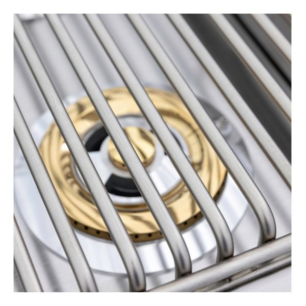 Close-up of a stainless steel gas burner with gold accents, featuring a grill grate overhead, showcasing modern cooking equipment design.