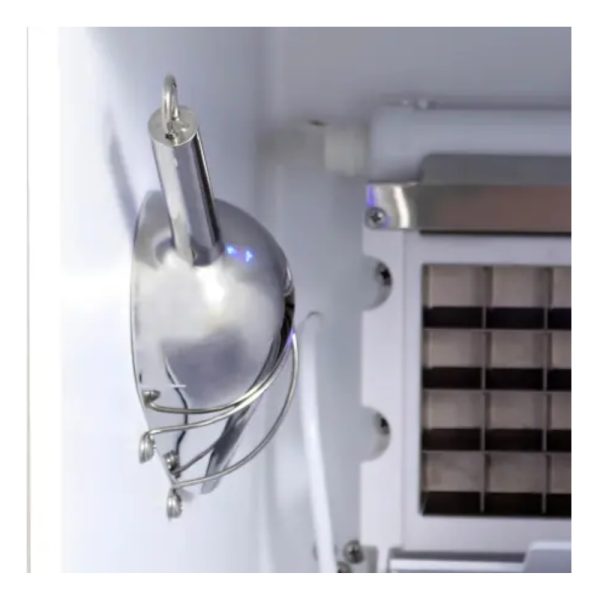 Silver ice scoop hanging inside a freezer with a grid for ice storage.