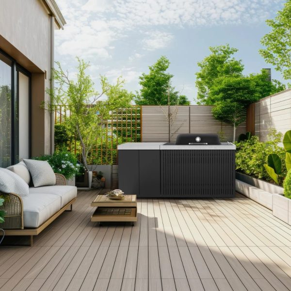 Modern outdoor patio featuring a stylish seating area, a sleek outdoor kitchen unit, and lush greenery, all set against a bright sky.