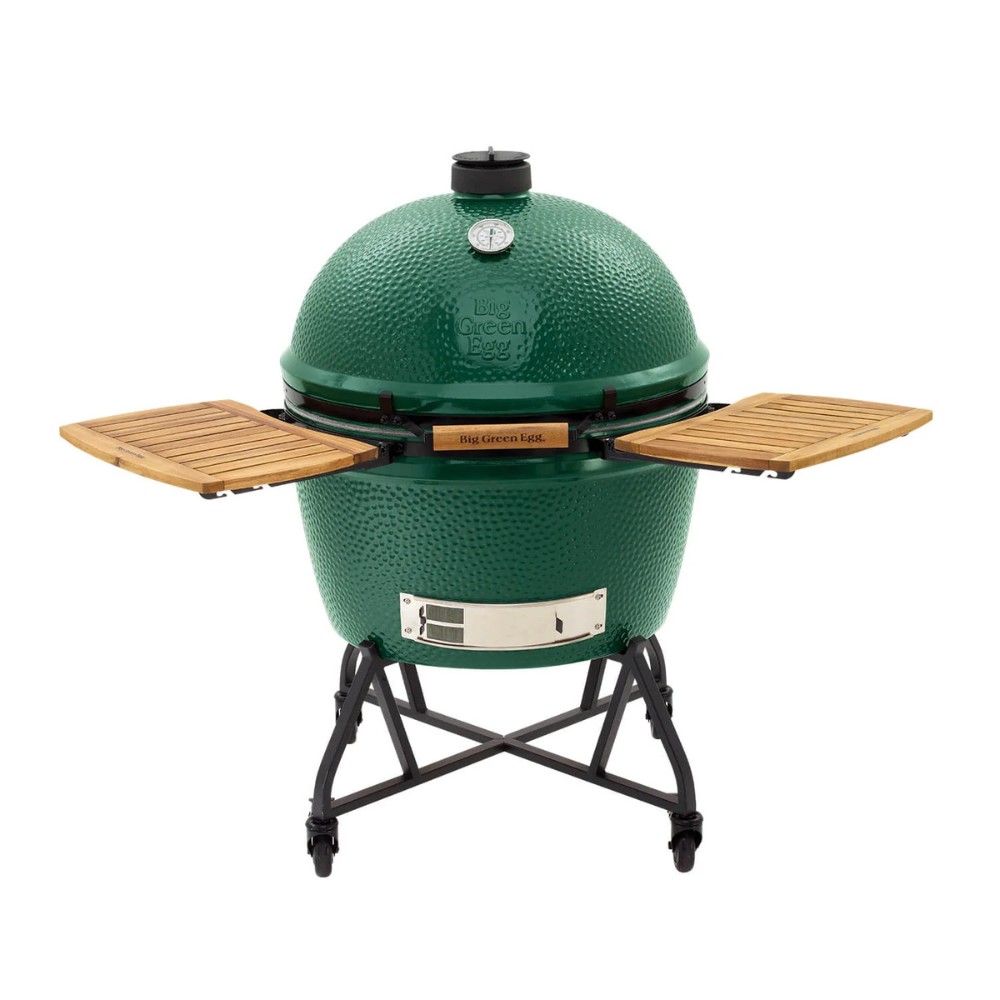 2194be3f-4fb8-42bb-9f03-ad2872a930ff.jpg Big Green Egg grill with a distinctive green ceramic body, wooden side shelves, and a temperature gauge on top, designed for versatile cooking methods like grilling, smoking, and baking.