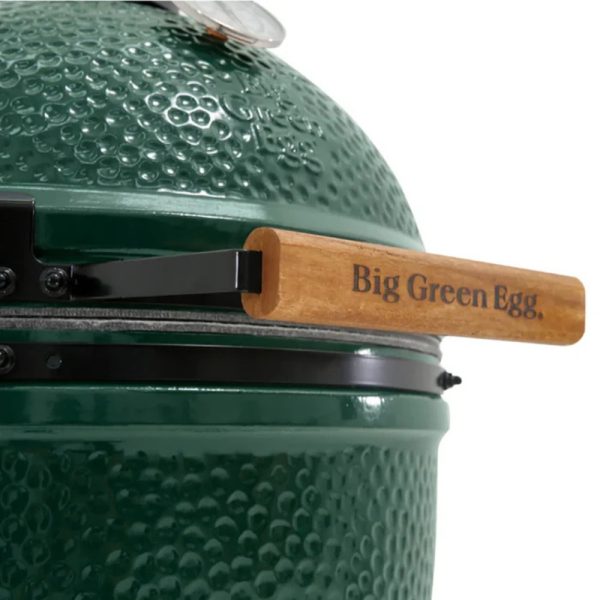 Close-up of a Big Green Egg grill featuring a textured green exterior and a wooden handle labeled "Big Green Egg."