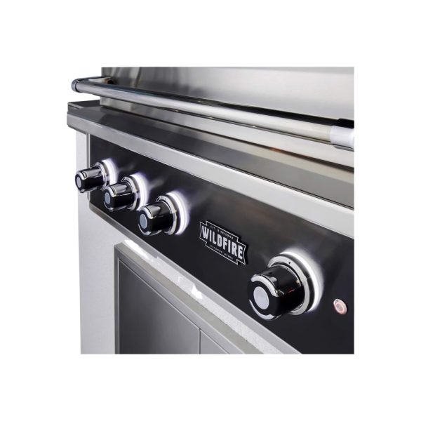 Close-up of a stainless steel outdoor grill control panel featuring four illuminated knobs and the Wildfire logo.